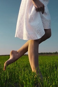 Woman walking on grass with healthy legs after vein treatment